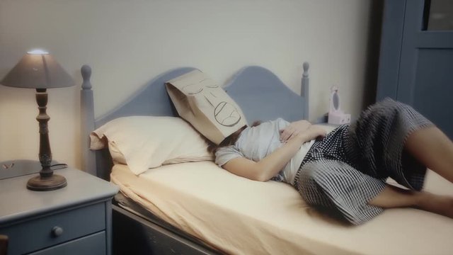 A breadbag face, alone in the bed, having a disturbed sleep, snoring. Medium shot.
