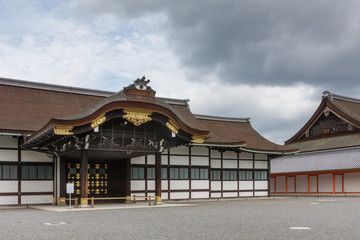 Fototapeta premium Kyoto, Japan - September 14, 2016: Highly decorated wooden entrance fronts the Shinmikurumayose hall at the Imperial Palace. Heavy skies.