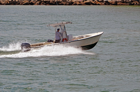 Small fishing boat powered by a single outboard engine heading west through Government Cut,Miami,Florida
