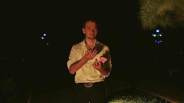 Conjurer Does Juggling with Cards High in Air in Dark Park