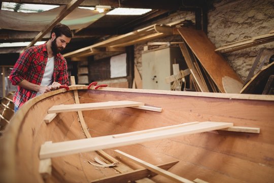 Carpenter preparing wooden boat frame in workshop