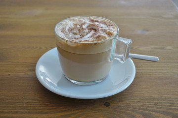 Cup of warm cappuccino coffee with cinnamon on top