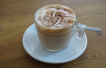 Cup of warm cappuccino coffee with cinnamon on top