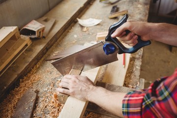 Man cutting a wooden plank