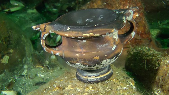 Greek crockery - kantharos among the amphora on the sea bottom (Black-glazed ware), close-up.
