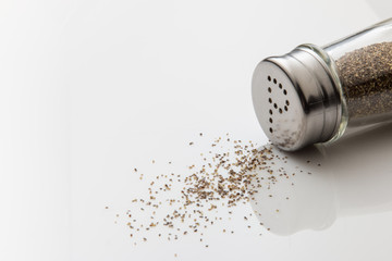 Pepper shaker tipped over on white background.