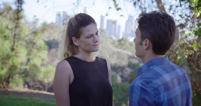 Young woman keeps her male companion in the friend zone while out together on a date in Los Angeles park.  She leaves, but he pulls her back at end.  Medium shot, recorded hand-held in real time.