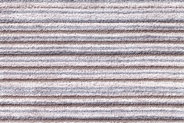 Light gray background of a knitted textile material. Fabric with a striped texture closeup.