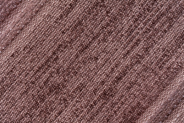 Fototapeta premium Brown background of a knitted textile material. Fabric with a striped texture closeup.