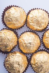 Chocolate ball in a gold foil paper on a background.