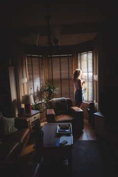Woman looking through window in living room
