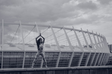 Naklejka premium Woman doing yoga exercises outdoors in the city.Beautiful brunette fit young woman wearing sportswear practicing yoga urban style.Asana, working out,fitness,sport,training and lifestyle concept