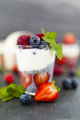 Chia seeds with yogurt and fresh berries fruit on stone background. 