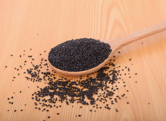 black sesame seeds in wooden spoon on wood table