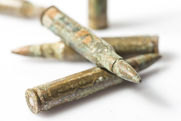 Old and rusty rifle bullets on a white background.