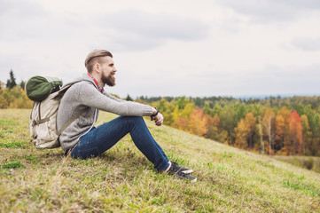 Naklejka na ściany i meble Young man traveler sitting on top of the hill. Travel and active lifestyle concept