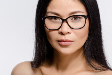 Portrait of beautiful Korean woman posing in glasses in studio. Attractive young lady looking at camera isolated on white background.