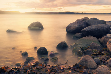 Long exposure landscape with stones in water over autumn sunset