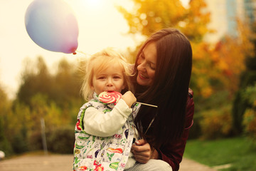 Beautiful child eats candy beside mom