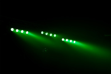 the green color of spotlights in smoke over black background