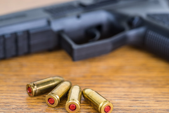 Close up view of bullets and handgun. Shallow depth of field. Pistol out of focus.