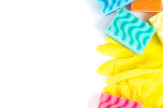 Close up of rubber gloves and sponges over white background