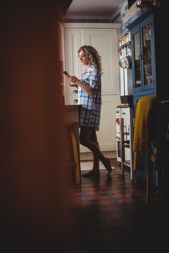Beautiful woman using mobile phone in kitchen