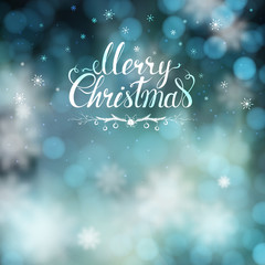 Blue Christmas greeting card with blur background and snowflakes. Big white hand-drawn inscription Merry Christmas on it.