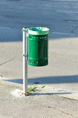 a green trash can on the street