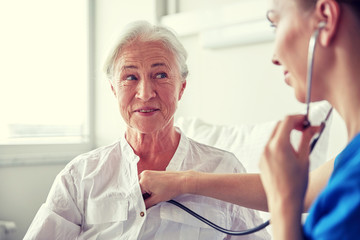 nurse with stethoscope and senior woman at clinic