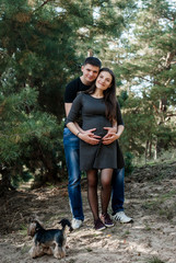 Pregnant woman and her husband lovely hugging on nature. Man kissing his young beautiful wife. Happy pregnant couple family.
