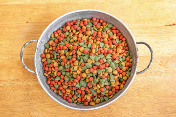 Dry dog food in aluminium bowl on wooden floor