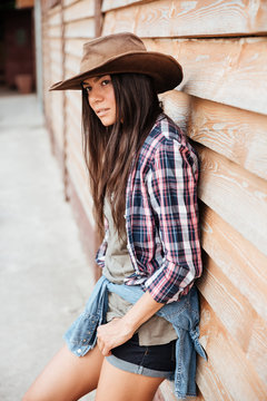 Beautiful young woman cowgirl in hat and plaid shirt