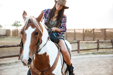 Smiling woman cowgirl riding a horse outdoors
