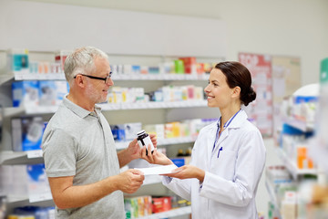 Obraz na płótnie Canvas pharmacist and senior man buying drug at pharmacy