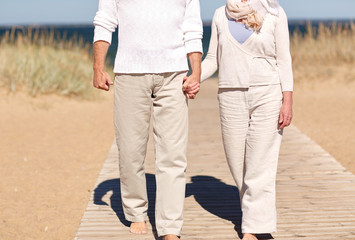 close up of senior couple walking on summer beach