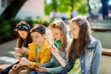 happy teenage friends with smartphones outdoors