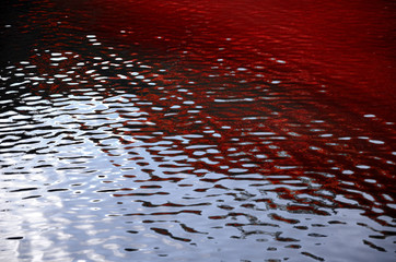 Blood red ripples and sky reflections on water