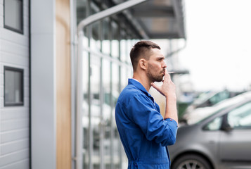auto mechanic smoking cigarette at car workshop