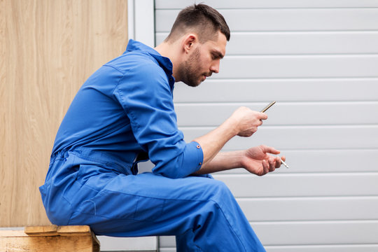 auto mechanic smoking cigarette at car workshop