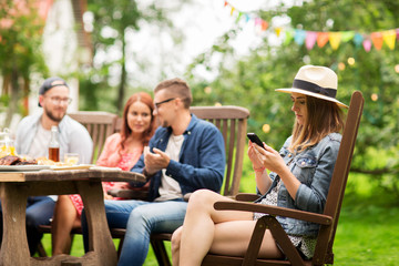 woman with smartphone and friends at summer party
