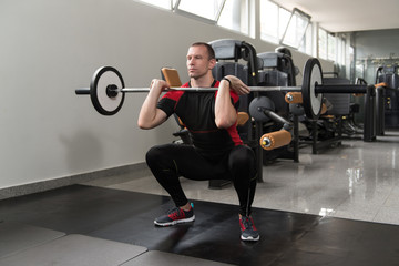 Fototapeta na wymiar Barbell Squat Workout For Legs In Gym