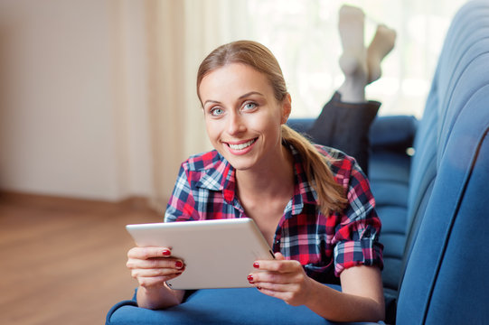 Attractive Young Woman Using Digital Tablet Pc On Sofa At Home