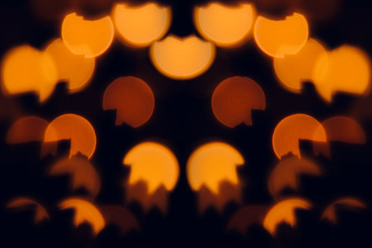 Orange festive abstract blurred background for Halloween. Orange circles bokeh  on black background.