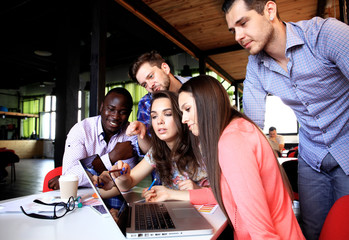 Portrait of happy young people in a meeting looking at camera and smiling. Young designers working together on a creative project