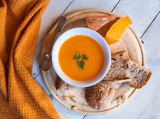 Pumpkin soup in a white bowl with bread