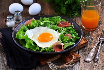 Fried egg with lettuce, arugula, parmesan and jamon. Rustic food.
