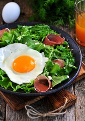 Fried egg with lettuce, arugula, parmesan and jamon. Rustic food.