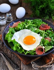 Fried egg with lettuce, arugula, parmesan and jamon. Rustic food.