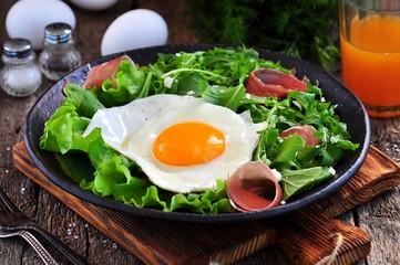 Fried egg with lettuce, arugula, parmesan and jamon. Rustic food.